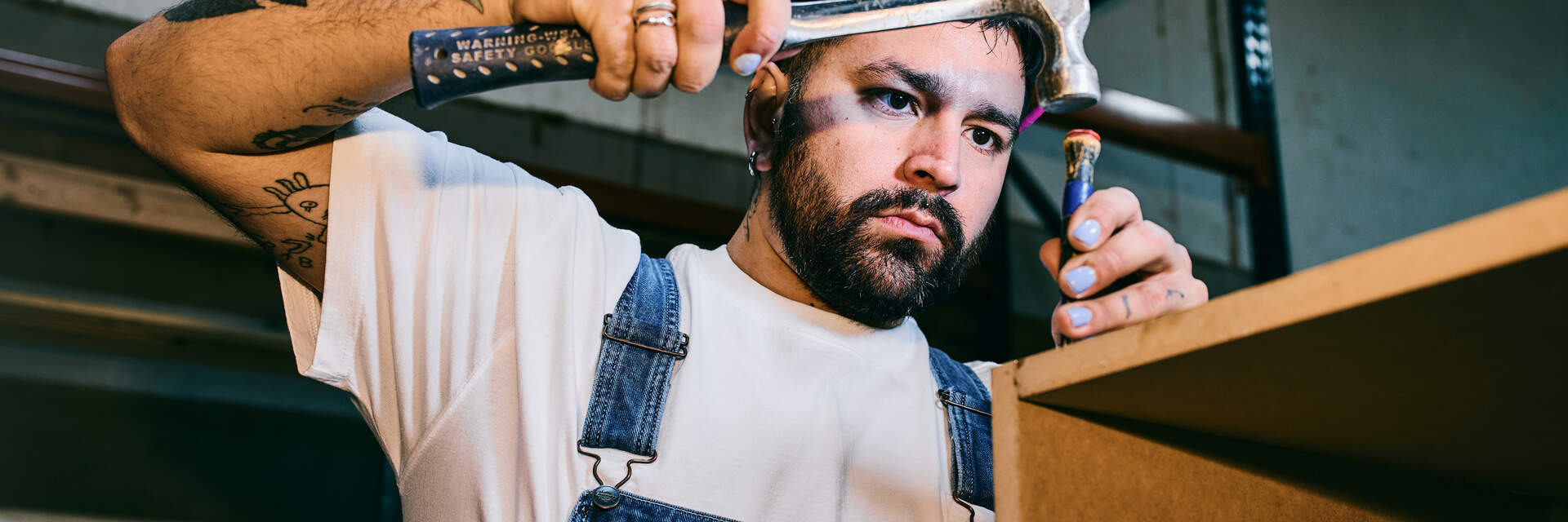 Bearded man in overalls doing wood working