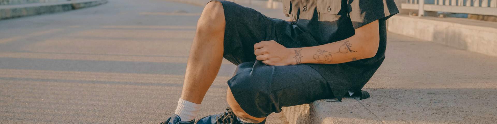 Man siting on curb in dickies work shorts