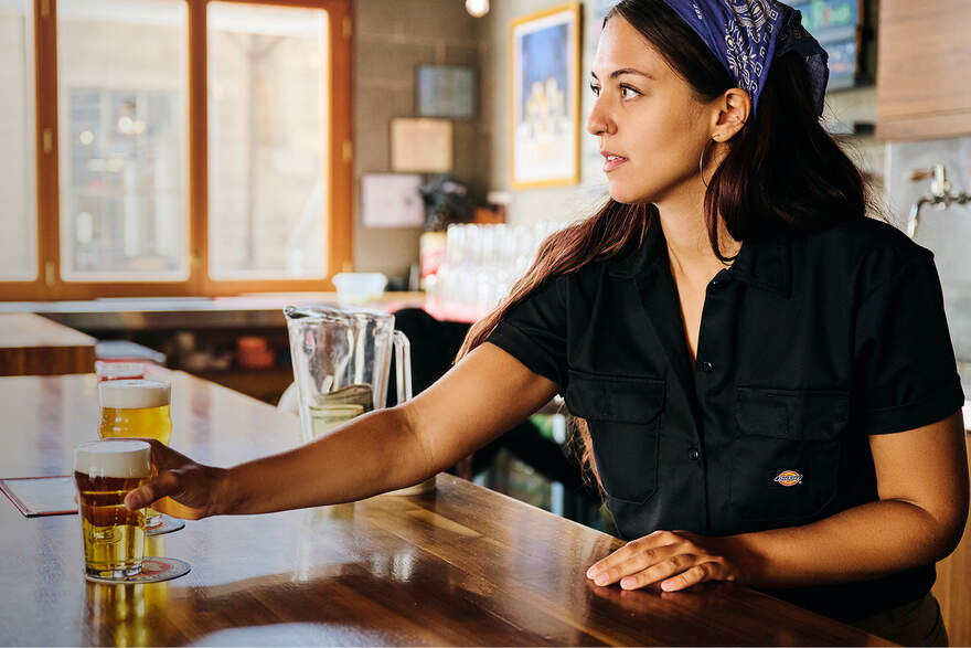 Woman working a bar wearing a bandana and Dickies work shirt