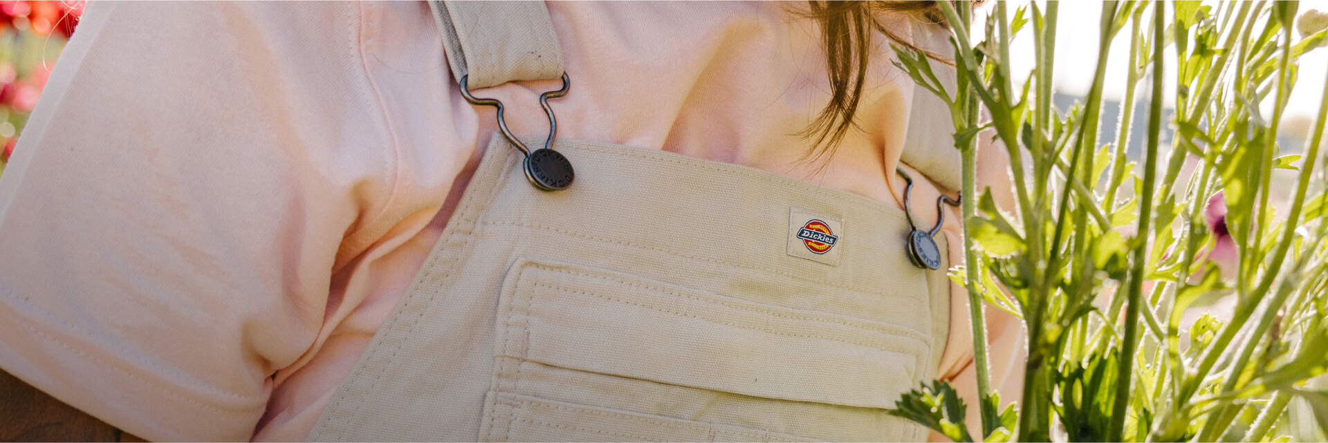 Woman in khaki overalls in field of flowers