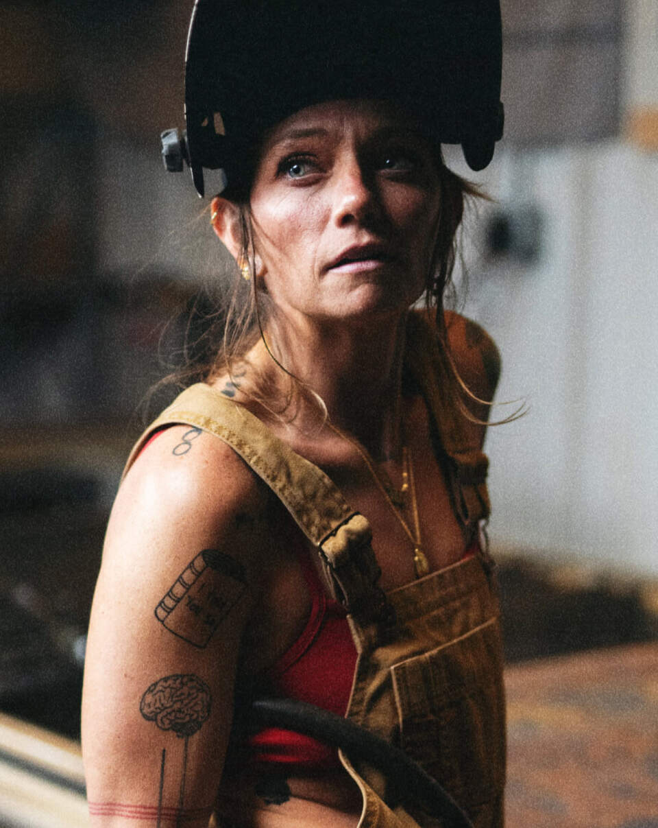 Rae Ripple in welding helmet and Khaki overalls