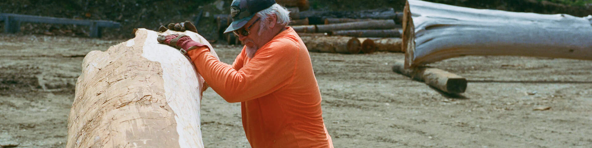Man in bright orange shirt leaning on boulder