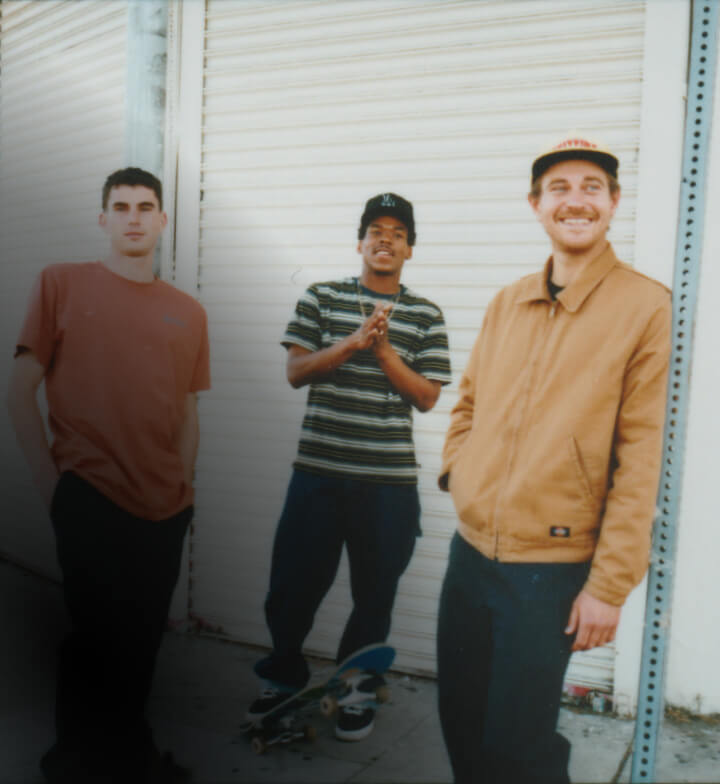 Three skaters posing for a candid shot next to a warehouse
