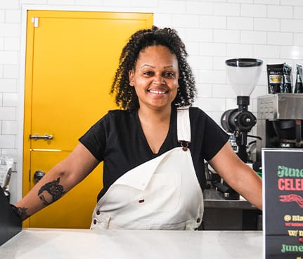 woman in overalls behind a coffee counter