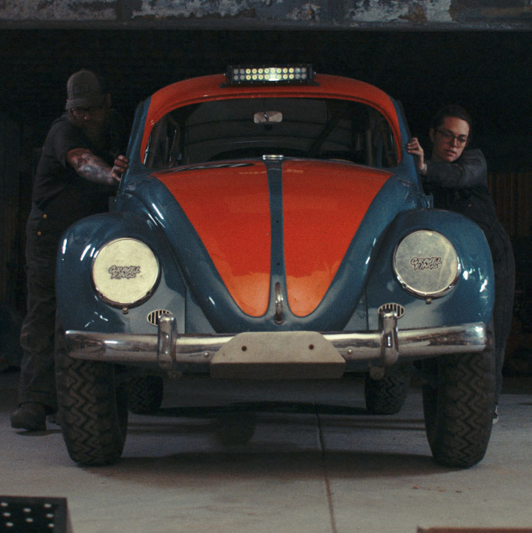 JJ and his daughter pushing a car in a garage setting.