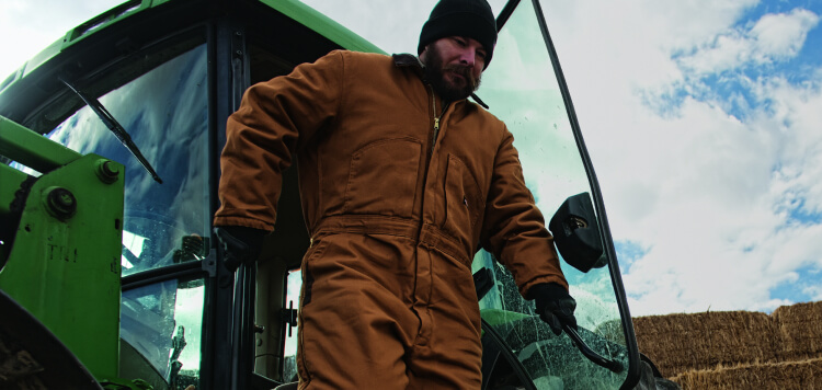 a man wearing duck coveralls while leaving a vehicle