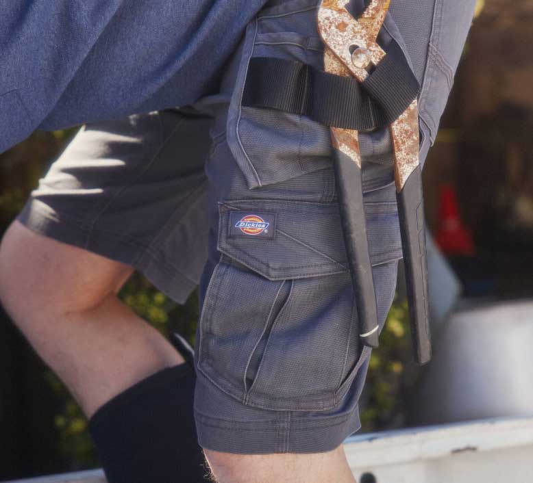 A close up of a wrench in the loops of work shorts.
