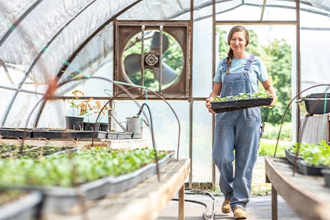 ABOVE: Monica takes care of her daily duties in the green house wearing her durable pinstriped overalls paired with a t-shirt.