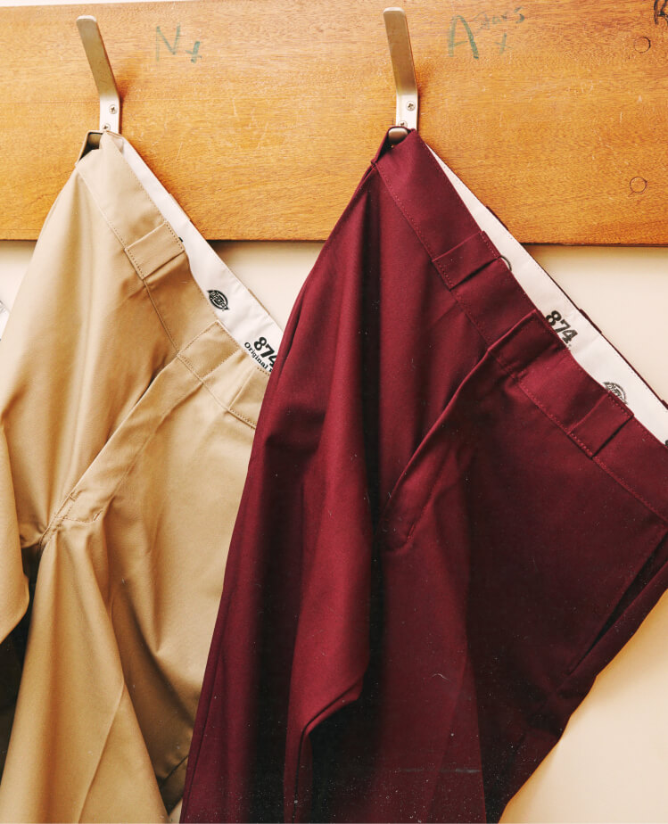 874 Signature Dickies pants hanging from clothing hooks.
