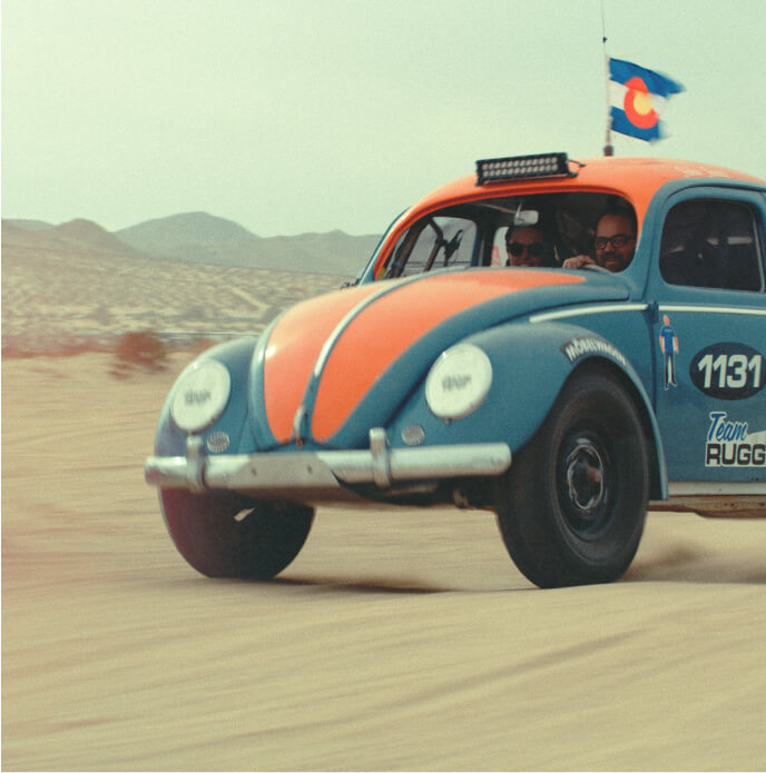 A VW beetle driving in the desert.