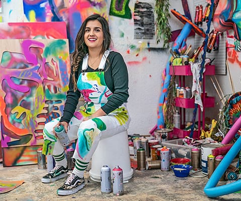 Artist wearing customized white women’s overalls in her art studio.