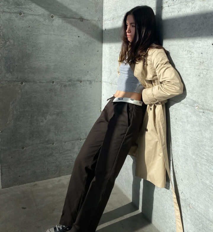 A woman leaning her back on a wall wearing an outtucked 874 pant