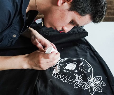 Erik Gomez hand painting one of his designs onto a Dickies Coverall