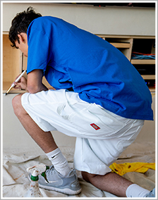 Man turned away and kneeling with white shorts and a blue shirt