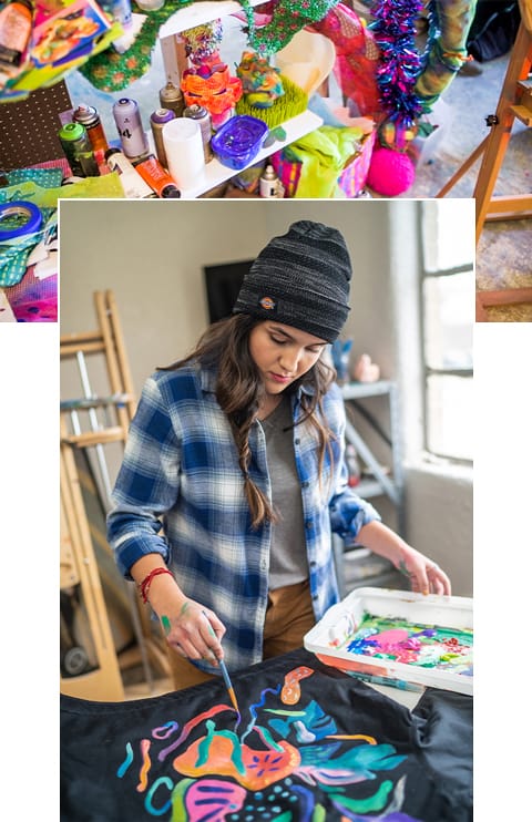 Artist painting colorful design on the back of a black jacket.