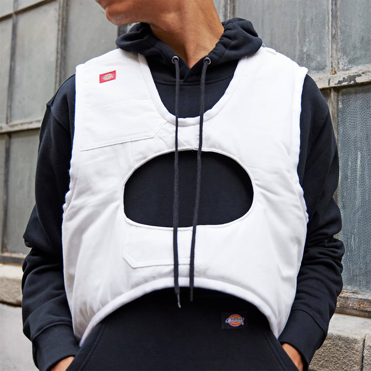 A white vest altered with a hole cut in the center worn on a model.