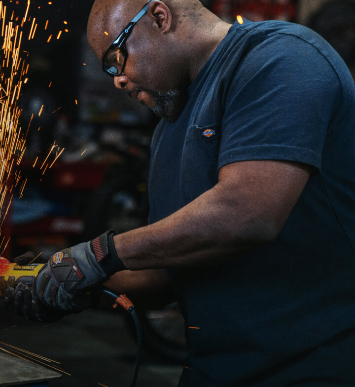 A worker using an electric tool in a workshop.