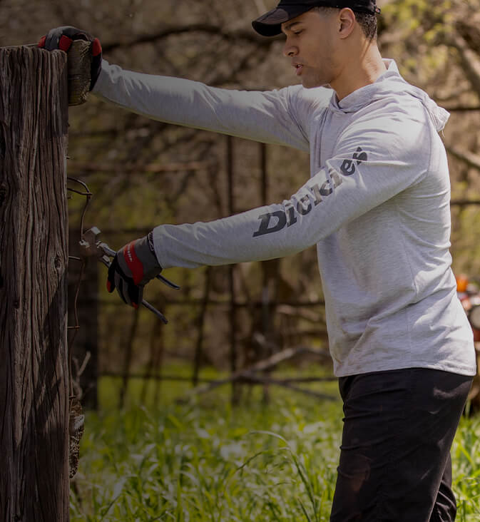 a man working on an outdoor fence in a white dickies shirt