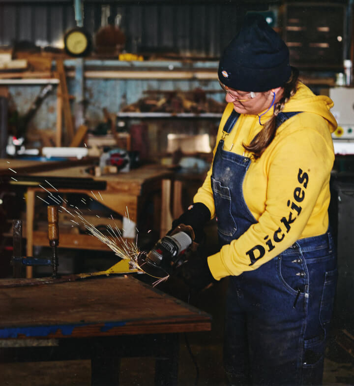 A woman using a grinding tool in a workshop.