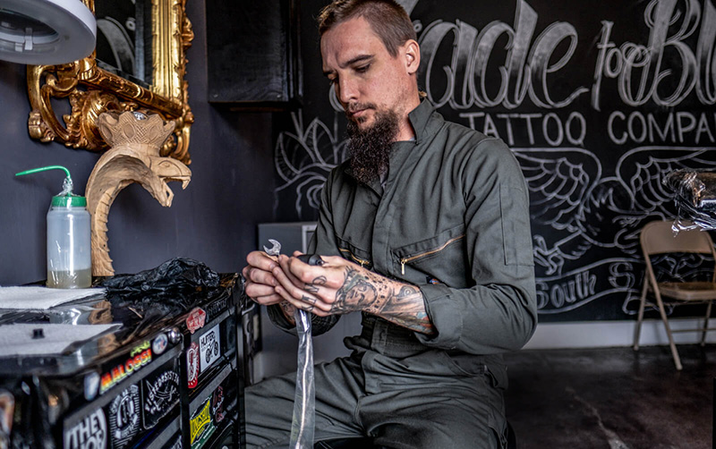 person wearing gray coveralls setting up a tatoo machine