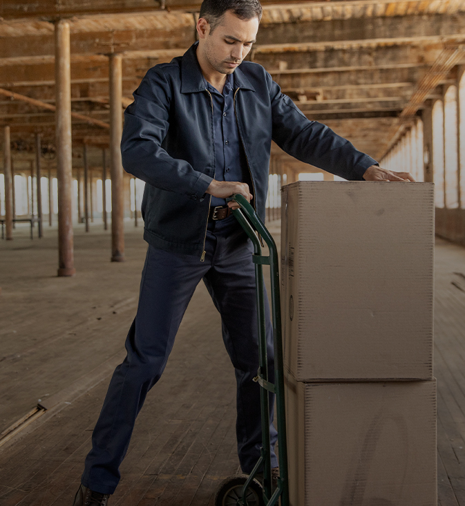 a worker using a dolly to move boxes