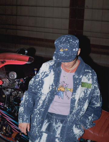 A man crouching and leaning against a motorcycle.