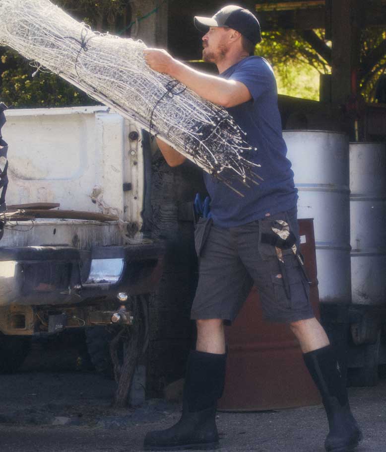 A worker wearing 365 Tech Duck shorts throwing fencing into the bed of a truck.