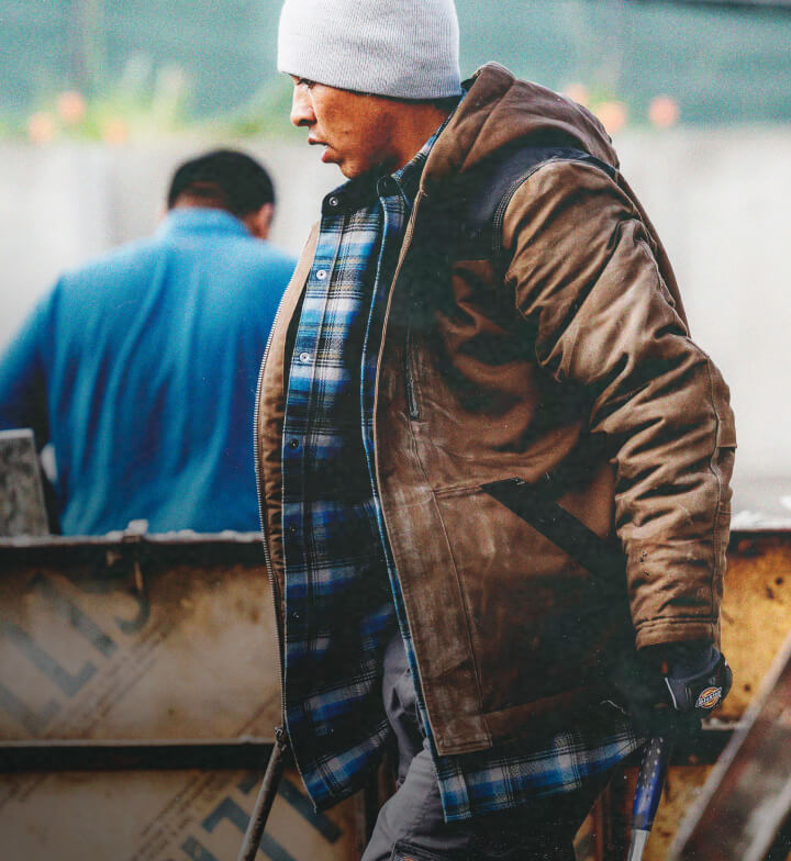 A man wearing a brown work jacket outside.