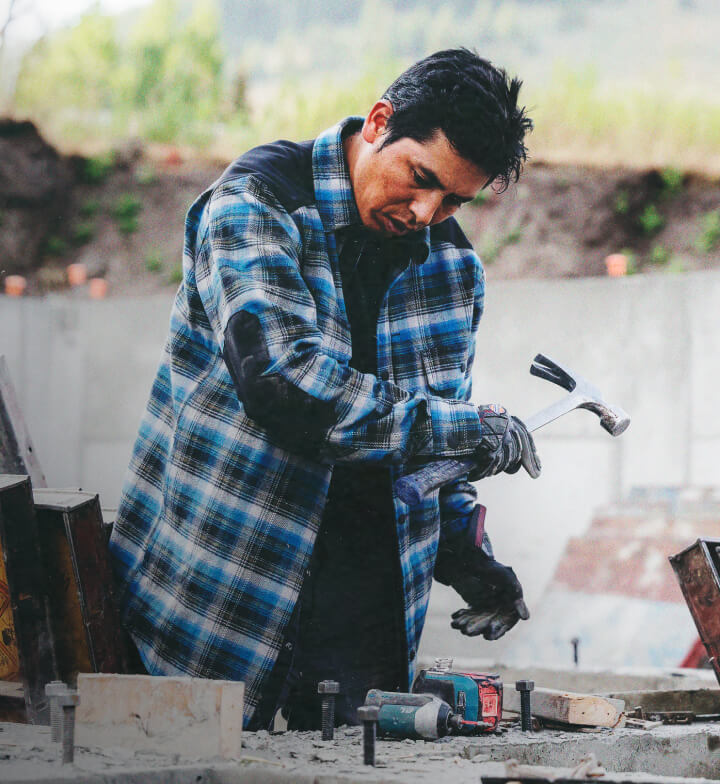 A worker using a hammer on a construction site.