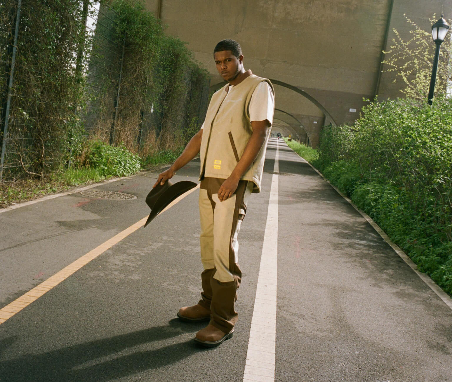 A man standing on a sidewalk wearing new york sunshine and dickies clothing