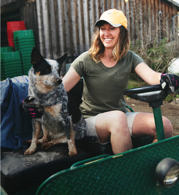 A woman driving a small vehicle while petting a dog.