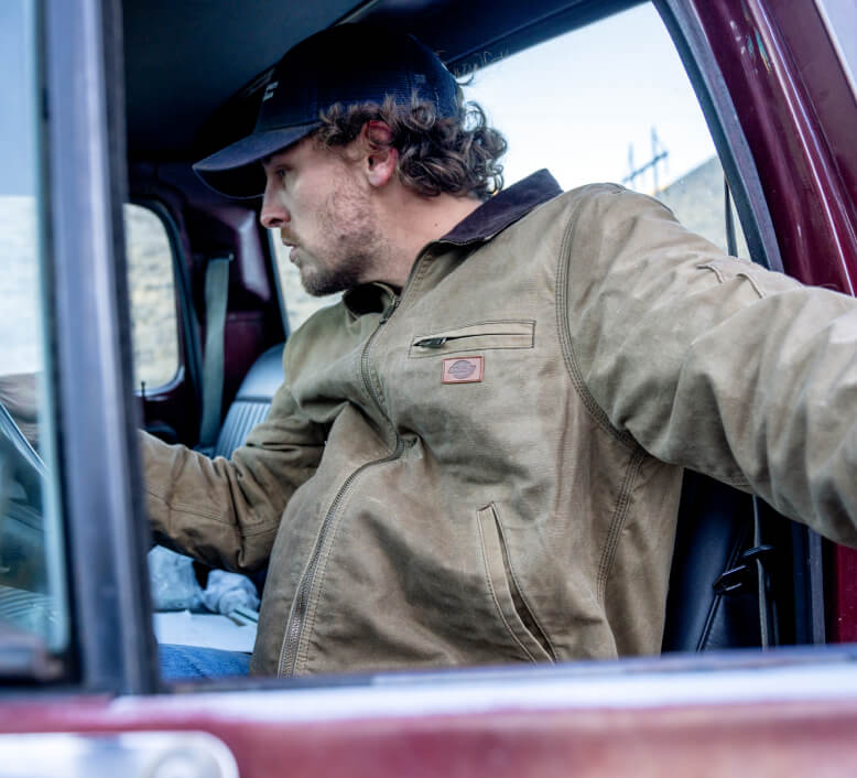 A worker getting into a truck to check their phone.