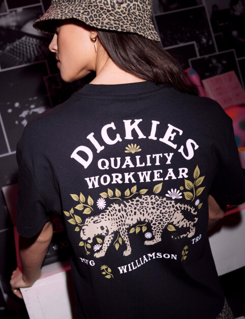 A woman wearing a tee shirt with the words 'Dickies Quality Workwear' on the back.
