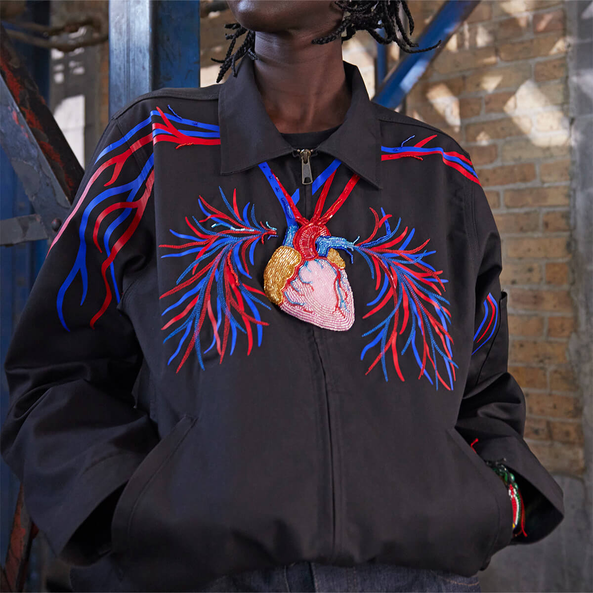 An eisenhower jacket altered with a painting of a heart and veins on it worn on a model.