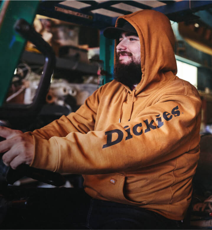 A man wearing a dickies hoodie in a vehicle.