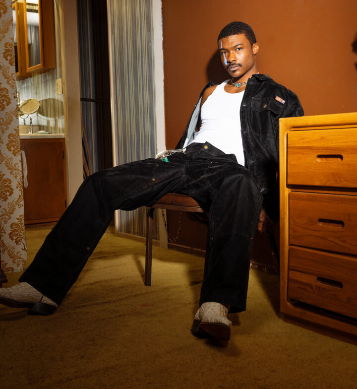 A man sitting on a chair next to a wall in a room.